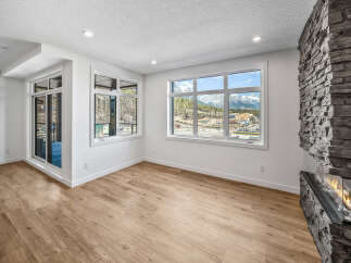 Experience breathtaking mountain views from this stunning living room, featuring a modern gas fireplace with a striking stone surround.