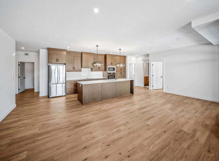 Experience modern living in this spacious open-concept kitchen and living area, featuring sleek wooden cabinetry and a large island perfect for entertaining.