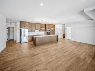 Experience modern living in this spacious open-concept kitchen and living area, featuring sleek wooden cabinetry and a large island perfect for entertaining.