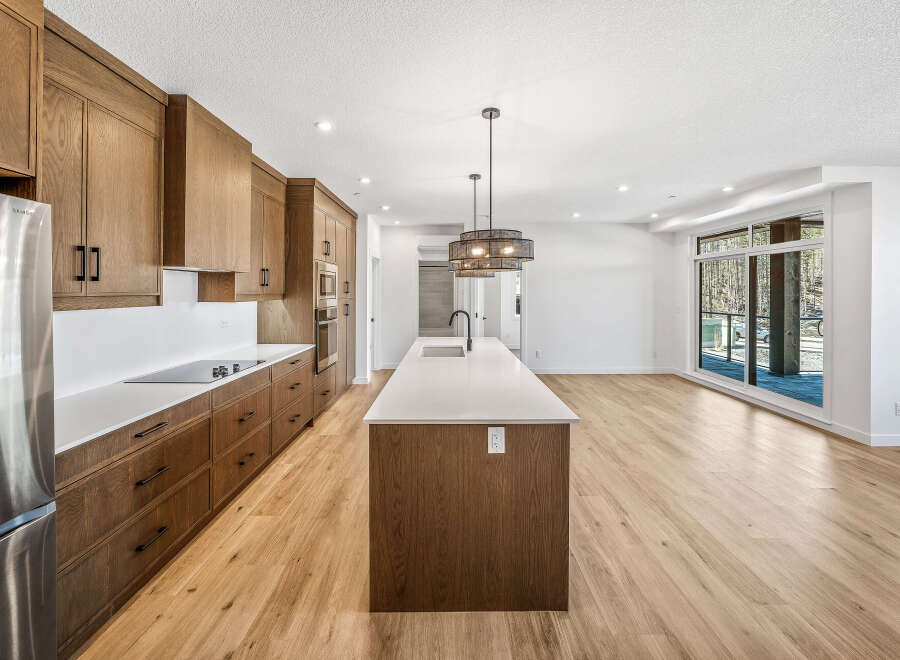 Experience modern living in this stunning kitchen featuring sleek, custom wood cabinetry and a spacious island with a waterfall countertop.