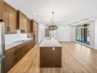 Experience modern living in this stunning kitchen featuring sleek, custom wood cabinetry and a spacious island with a waterfall countertop.