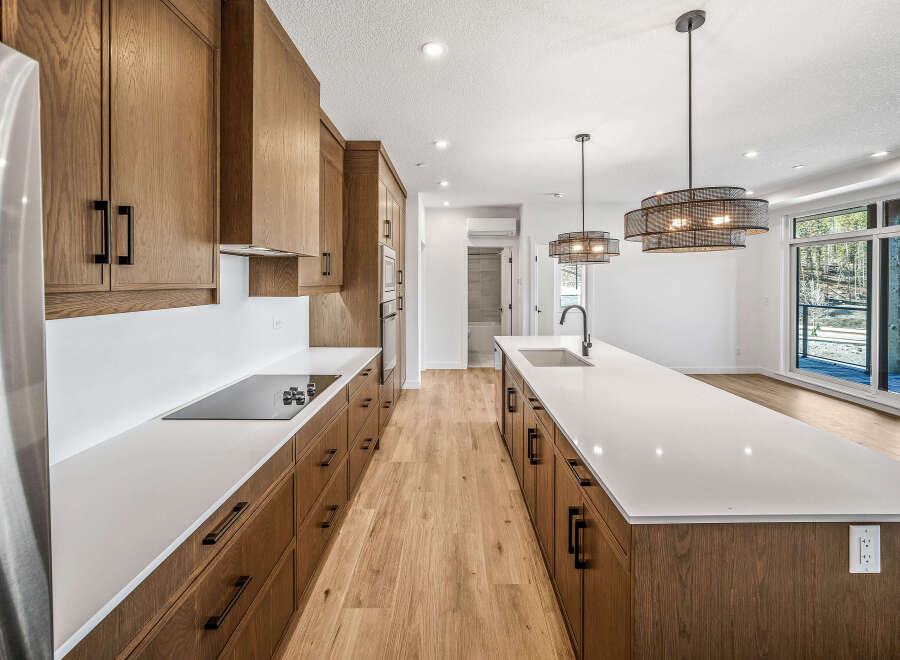 Experience modern living in this stunning kitchen featuring sleek, custom wood cabinetry and expansive quartz countertops.
