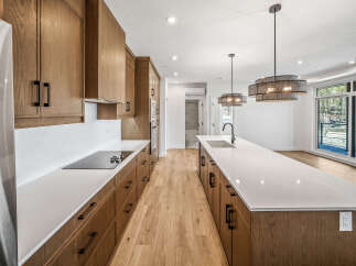 Experience modern living in this stunning kitchen featuring sleek, custom wood cabinetry and expansive quartz countertops.