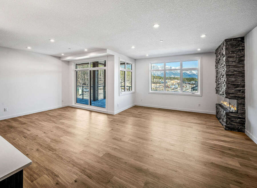 Experience breathtaking mountain views from this stunning living room, featuring a modern stone fireplace and expansive windows.