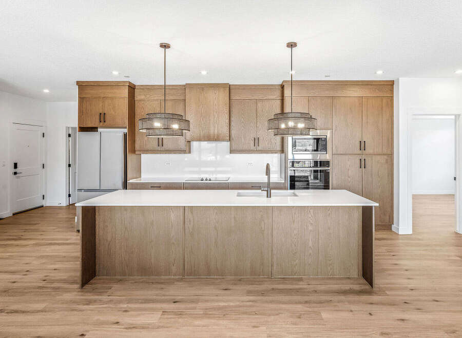 Experience modern living in this stunning kitchen featuring sleek, light wood cabinetry and a spacious island with a waterfall countertop.