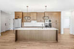 Experience modern living in this stunning kitchen featuring sleek, light wood cabinetry and a spacious island with a waterfall countertop.