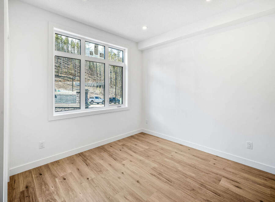 Discover modern living in this bright and airy room featuring a large window with scenic views of a wooded hillside.