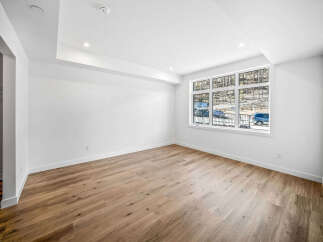 Experience modern living in this bright and airy space, featuring a stunning tray ceiling with recessed lighting and a large, picturesque window that floods the room with natural light.