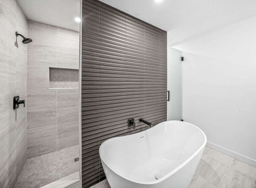 Experience modern luxury in this stunning bathroom, featuring a sleek freestanding bathtub and a spacious walk-in shower with elegant tilework.