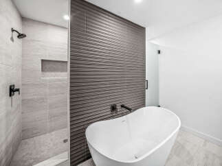 Experience modern luxury in this stunning bathroom, featuring a sleek freestanding bathtub and a spacious walk-in shower with elegant tilework.