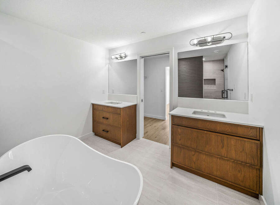 This luxurious bathroom features a freestanding soaking tub and dual vanities with rich wood cabinetry.