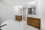 This luxurious bathroom features a freestanding soaking tub and dual vanities with rich wood cabinetry.