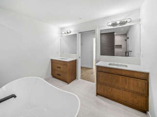 This luxurious bathroom features a freestanding soaking tub and dual vanities with rich wood cabinetry.
