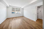 Experience modern living in this bright and airy room featuring a large window with scenic views and elegant hardwood flooring.