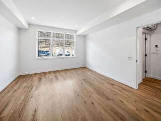 Experience modern living in this bright and airy room featuring a large window with scenic views and elegant hardwood flooring.