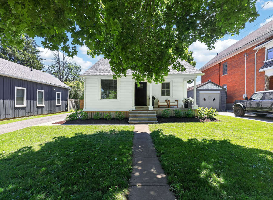 Charming white cottage-style home with a welcoming front porch, perfect for enjoying the outdoors.