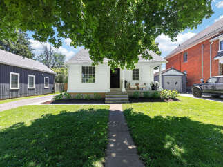 Charming white cottage-style home with a welcoming front porch, perfect for enjoying the outdoors.