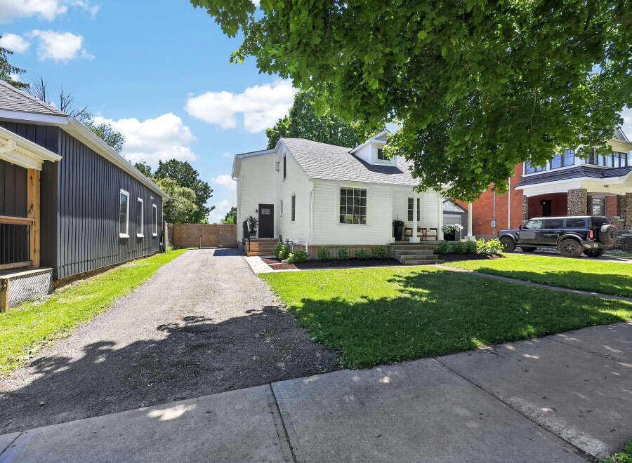 Charming white home with a dark-paneled adjacent structure, offering a unique architectural blend.
