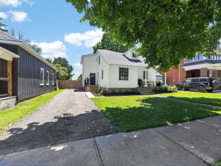 Charming white home with a dark-paneled adjacent structure, offering a unique architectural blend.