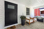 Step onto the charming porch of this inviting home, featuring a sleek black front door and a welcoming doormat.
