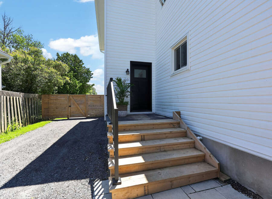 Discover this charming home featuring a welcoming entrance with a black door and a stylish black railing leading up a wooden staircase.