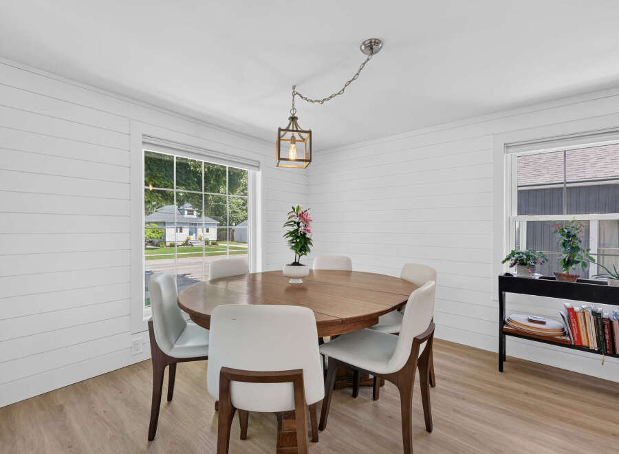 This charming dining room features a round wooden table surrounded by sleek white chairs, perfect for intimate gatherings.