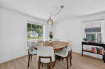This charming dining room features a round wooden table surrounded by sleek white chairs, perfect for intimate gatherings.