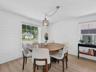 This charming dining room features a round wooden table surrounded by sleek white chairs, perfect for intimate gatherings.