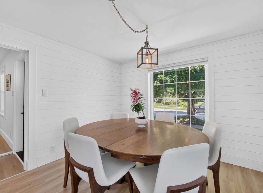 This dining room features a charming wooden table surrounded by sleek white chairs, perfect for intimate gatherings.