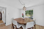 This dining room features a charming wooden table surrounded by sleek white chairs, perfect for intimate gatherings.