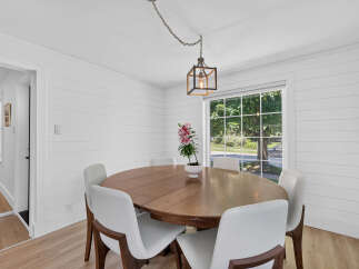 This dining room features a charming wooden table surrounded by sleek white chairs, perfect for intimate gatherings.