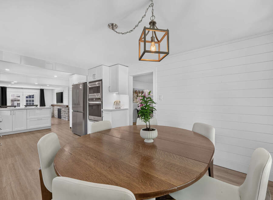 This open-concept dining area features a round wooden table with four white chairs, perfect for family meals.