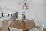 This open-concept dining area features a round wooden table with four white chairs, perfect for family meals.