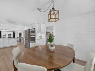 This open-concept dining area features a round wooden table with four white chairs, perfect for family meals.