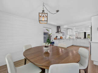 This bright and airy dining area seamlessly transitions into a modern white kitchen, perfect for entertaining.