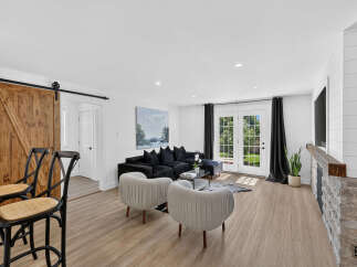 Experience modern living in this beautifully appointed living room, featuring a plush black sectional sofa and elegant grey accent chairs.