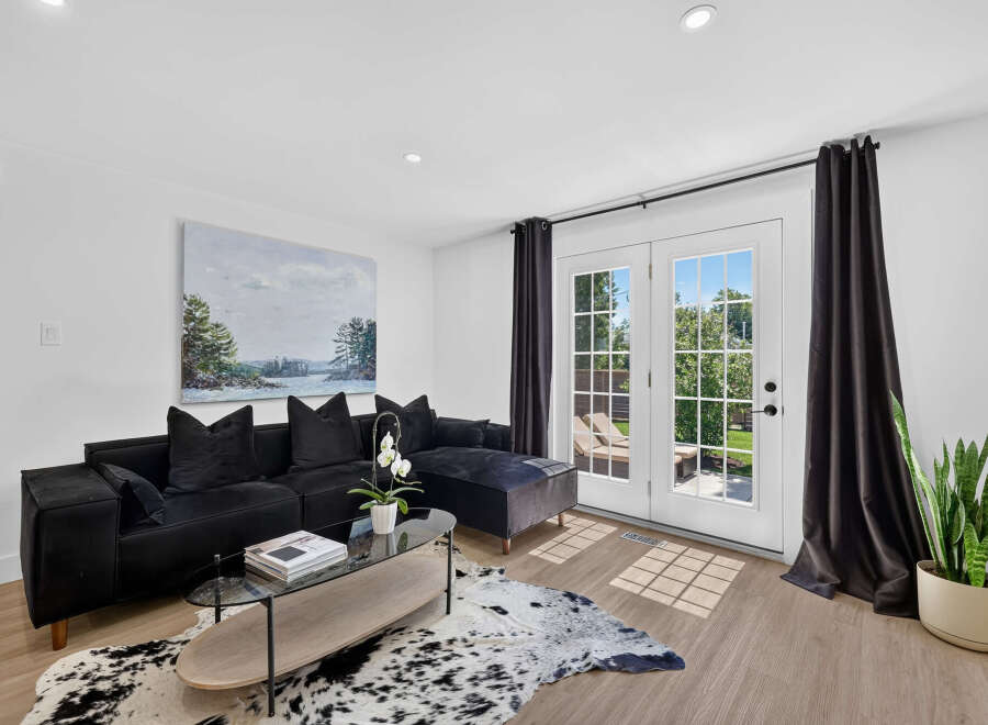 Step into this modern living room featuring a plush black sectional sofa adorned with velvet pillows, perfect for cozy evenings.