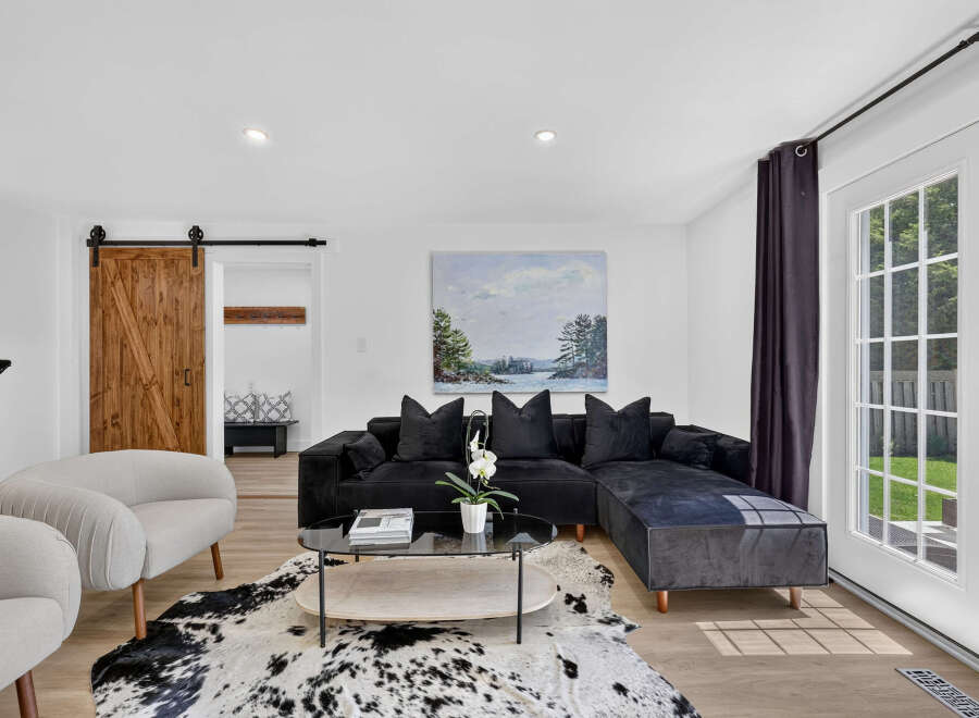 Step into this inviting living room featuring a plush black sectional sofa adorned with velvet pillows, perfect for cozy evenings.