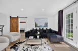Step into this inviting living room featuring a plush black sectional sofa adorned with velvet pillows, perfect for cozy evenings.