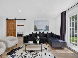Step into this inviting living room featuring a plush black sectional sofa adorned with velvet pillows, perfect for cozy evenings.