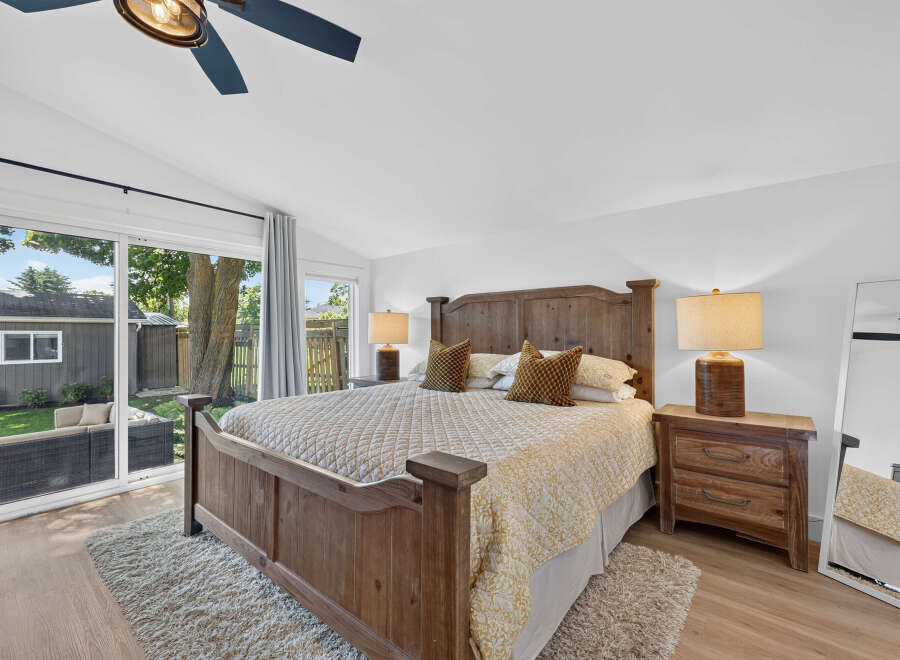 Experience ultimate comfort in this beautifully appointed bedroom, featuring a rustic wooden bed frame and a plush, textured rug.
