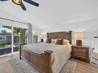 Experience ultimate comfort in this beautifully appointed bedroom, featuring a rustic wooden bed frame and a plush, textured rug.