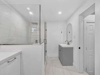 Experience modern luxury in this stunning bathroom featuring a spacious glass-enclosed shower with a rainfall showerhead.