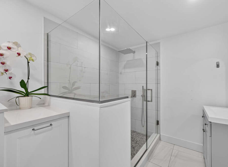 Experience modern luxury in this stunning bathroom featuring a spacious glass-enclosed shower with a rainfall showerhead and sleek tilework.