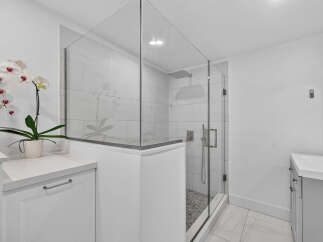 Experience modern luxury in this stunning bathroom featuring a spacious glass-enclosed shower with a rainfall showerhead and sleek tilework.