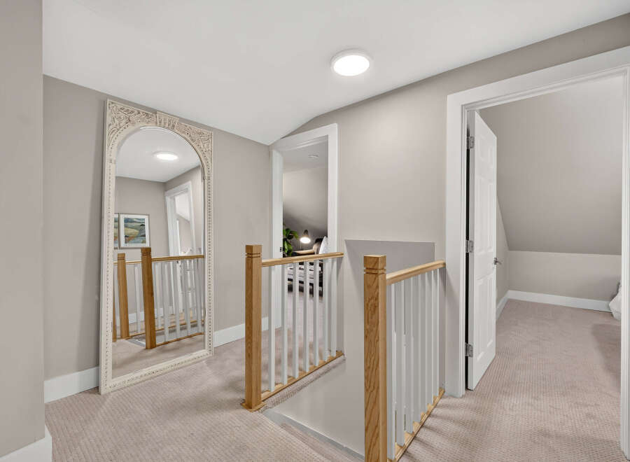 This spacious hallway features a large ornate mirror reflecting the light from a modern ceiling fixture.