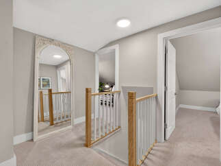 This spacious hallway features a large ornate mirror reflecting the light from a modern ceiling fixture.