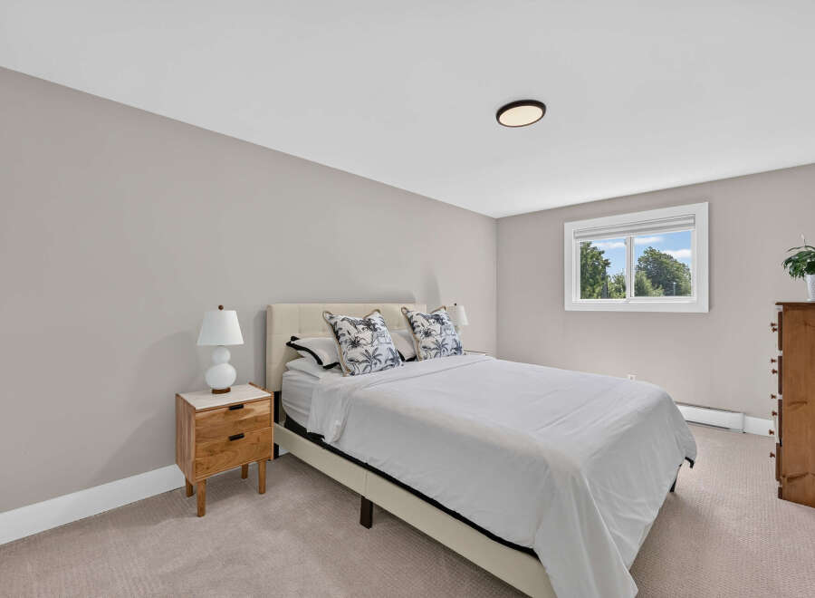 Discover comfort and style in this inviting bedroom, featuring a plush bed with decorative pillows and a sleek nightstand.