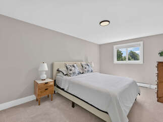 Discover comfort and style in this inviting bedroom, featuring a plush bed with decorative pillows and a sleek nightstand.