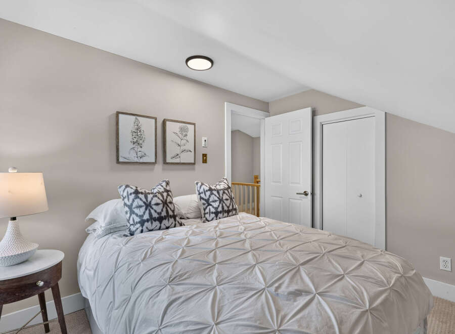 Discover comfort and style in this inviting bedroom, featuring a plush queen-size bed adorned with decorative pillows and a textured duvet.